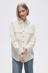 Camisa color crudo de viscosa, corte holgado, con cuello camisero, cierre frontal con botones, manga larga y dos bolsillos con solapa en el pecho.