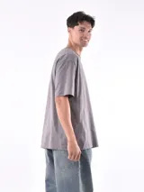 Remera gris de corte oversized, cuello redondo y mangas cortas. 