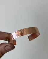 Pulsera de cobre hecha a mano, con acabado martillado y diseño abierto ajustable.
