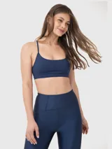 Top deportivo de lycra gris con tirantes finos cruzados en la espalda y almohadillas removibles.
