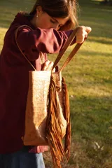 Bolso maxi marrón de cuero con flecos y botón de guampa. Tiene bolsillo interior y cierre metálico.