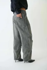 Pantalón jean gris de tiro medio con calce amplio, bolsillos delanteros y traseros, recortes en las piernas, trabillas para cinturón y cierre con botón y cremallera.