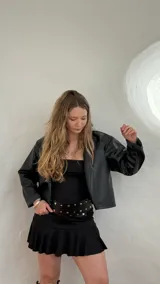 Campera corta de ecocuero color negro, con cuello clásico, cierre frontal con cremallera y mangas largas.