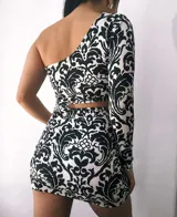 Vestido negro y blanco, con un solo hombro y corte en la cintura que resalta la figura.