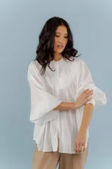 Camisa blanca de algodón con cuello mao, mangas largas abullonadas y costuras frontales.