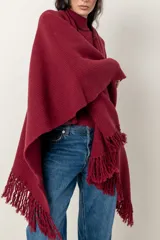 Ruana de tejido de punto color bordó, con cuello alto y terminaciones con flecos largos.