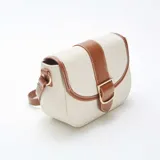 Bolso bandolera de lona color beige con detalles en cuero marrón. Tiene correa larga ajustable y cierre con hebilla dorada.