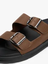 Sandalias marrones de cuero con doble tira y hebillas metálicas plateadas con el logo de Tommy Hilfiger.