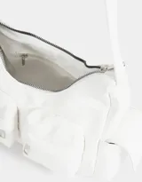 Bandolera blanca con asa de hombro regulable, cierre superior, doble bolsillo frontal con cierre y bolsillos laterales con solapa y broche con botón.