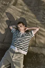 Polo de punto color crema con rayas horizontales verde oscuro, cuello clásico y cierre de botones.