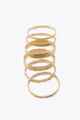 Pack de pulseras rígidas doradas con textura irregular.