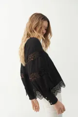 Blusa negra con escote cuadrado, mangas largas abullonadas con detalles de encaje y galón de encaje en el ruedo.