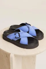 Sandalias bajas con plataforma negra y tiras cruzadas de tela color celeste con hebilla ajustable.