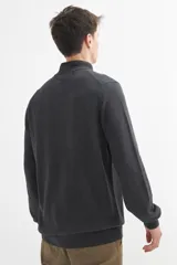 Campera negra de tejido de punto, con cuello alto, cierre frontal y mangas largas.