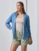 Camisa celeste de tencel con cuello con solapa, escote en V, abertura central con botones, bolsillo aplicado en el frente y ruedo desflecado.