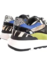 Championes deportivos de caña baja con cierre de cordones y detalles de superposición de paneles de diferentes texturas y colores. Presentan un patrón de líneas onduladas y bloques de color contrastante en tonos neutros y vibrantes.