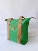 Bolso tipo tote de lona color fucsia con asas de cuero marrón, bolsillo interno y externo.