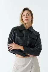 Sobrecamisa cropped de cuero sintético color negro, con cuello clásico, cierre frontal con botones, mangas largas y bolsillos frontales con solapa.