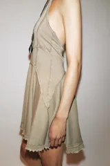 Vestido corto color beige con cuello halter y falda con godets.
