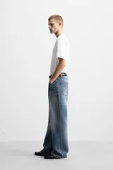 Pantalón de jean celeste con efecto lavado, corte flare fit y caída baggy desde la rodilla hasta el tobillo. Tiene cinco bolsillos y cierre frontal con botones.
