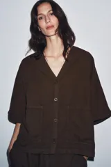 Camisa marrón de algodón con escote en V, manga corta, bolsillos de parche en el frente y cierre frontal con botones.