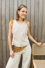 Chaleco color crema de tejido de punto calado, con cuello redondo y detalle de plumas en los hombros.