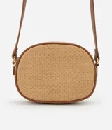 Cartera bandolera pequeña color beige con textura de paja y detalles en marrón. Tiene cierre de cremallera, bolsillo externo y asa larga regulable con hebilla.
