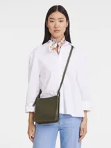 Bandolera Longchamp modelo Le Foulonné, color verde oliva, de cuero granulado, con correa ajustable para llevar al hombro o cruzada.