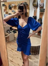 Vestido corto azul eléctrico con escote en V, mangas abullonadas 3/4, frunce central y volados en el ruedo.