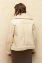 Campera gamulán color crema, con cuello y puños de corderito, cierre frontal con cremallera y bolsillos laterales.