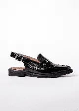 Mocasines color borgoña de cuero con punta fina, detalle de apliques metálicos y tira trasera con hebilla.