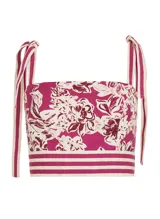 Crop top con estampado floral en tonos fucsia y blanco, breteles finos con lazos en los hombros y detalle de franjas horizontales en el bajo.