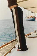 Pantalón tejido negro con rayas verticales color crema y marrón en los laterales y cintura elastizada.