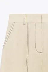 Pantalón de tiro alto color beige confeccionado con lino, de pierna recta, con bolsillos delanteros y falsos bolsillos de vivo en la espalda.