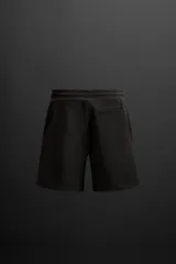 Bermuda jogger negra confeccionada en tejido de algodón con interior de rizo, cintura elástica ajustable con cordón y bolsillos laterales.