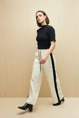Pantalón de jogging color crema con cintura elástica, cordón ajustable y franja lateral negra.