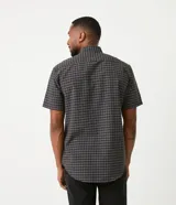 Camisa de hombre de corte clásico, color gris oscuro con estampado de cuadros blancos, cuello abotonado, manga corta y cierre frontal con botones blancos.