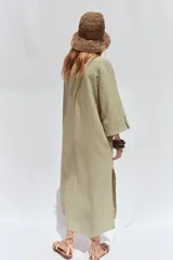 Vestido camisero blanco confeccionado en lino, de corte recto y largo midi. Presenta cuello camisero, mangas 3/4 con puños abotonados, cierre frontal con botones y abertura en el ruedo.