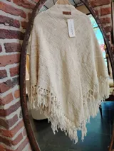 Chal triangular tejido con lana merino color crudo, con terminaciones de flecos largos.