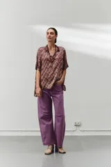 Blusa marrón con estampado abstracto, cuello camisero, mangas cortas, corte amplio y aberturas laterales.