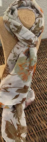 Chalina rectangular de tela traslúcida color blanco con estampado de flores y hojas en tonos marrón, naranja, verde y rosa.