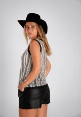 Blusa blanca de tejido calado, sin mangas y con cuello redondo ribeteado en negro.