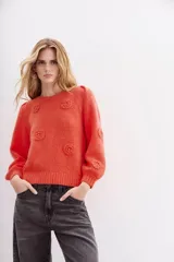 Sweater color coral de lana y mohair con calce holgado y mangas largas. Presenta frunces en hombros, escote, puños y ruedo en rib. Tiene aplicación de flores tejidas con detalle de strass.