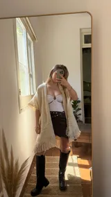 Ruana color crema tejida a mano en lana merino peinada, con diseño calado y flecos en el borde inferior.