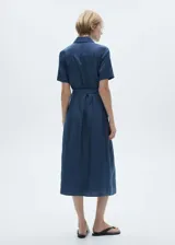 Vestido camisero midi color beige, de tela satinada, con cuello camisero, mangas cortas, dos bolsillos de parche en el pecho, lazo ajustable en la cintura y cierre frontal con botones.
