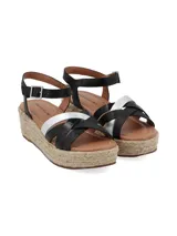 Sandalias de plataforma con suela de yute, tiras cruzadas de cuero negro y plateado, y pulsera al tobillo con hebilla metálica.