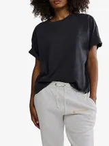 Remera negra de manga corta, corte cuadrado y holgado, con bolsillo en el pecho y logo estampado.