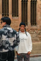 Buzo blanco de manga larga con cuello polo y estampado con la palabra "Container" en cursiva y la leyenda "BS. AS. // ARG" en letras pequeñas.