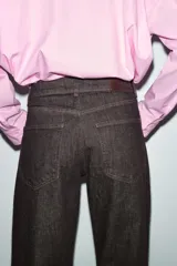 Jeans de tiro medio, color negro lavado con efecto desgastado, corte recto y holgado (loose straight), con cinco bolsillos y cierre frontal de cremallera y botón.