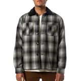 Campera a cuadros gris y negra con cuello de pana negro, cierre con botones, bolsillos de parche en el pecho y corte recto.